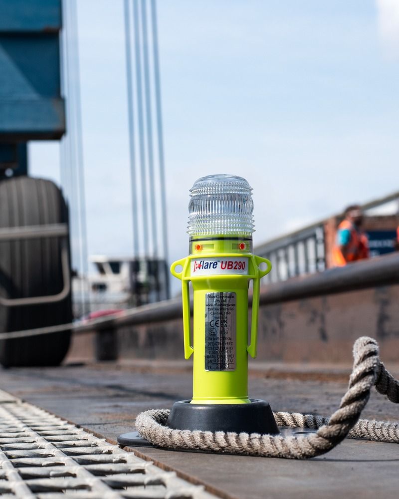 Yellow LED hazard light on a quayside beside coiled mooring rope