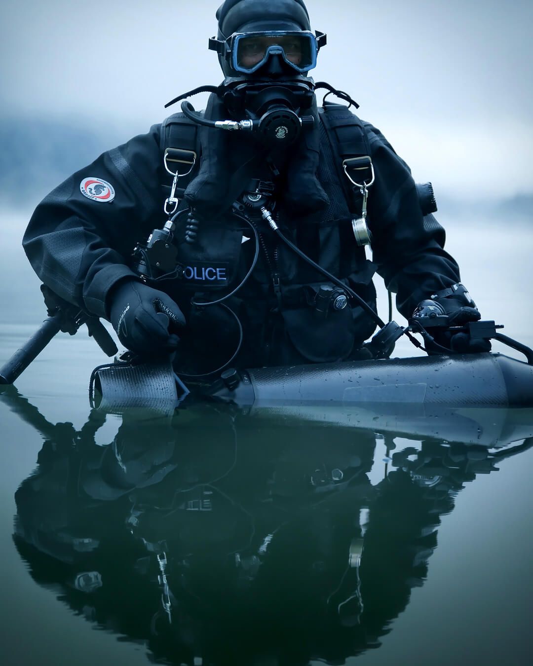 Diver in a black Ursuit drysuit and full-face mask in calm water